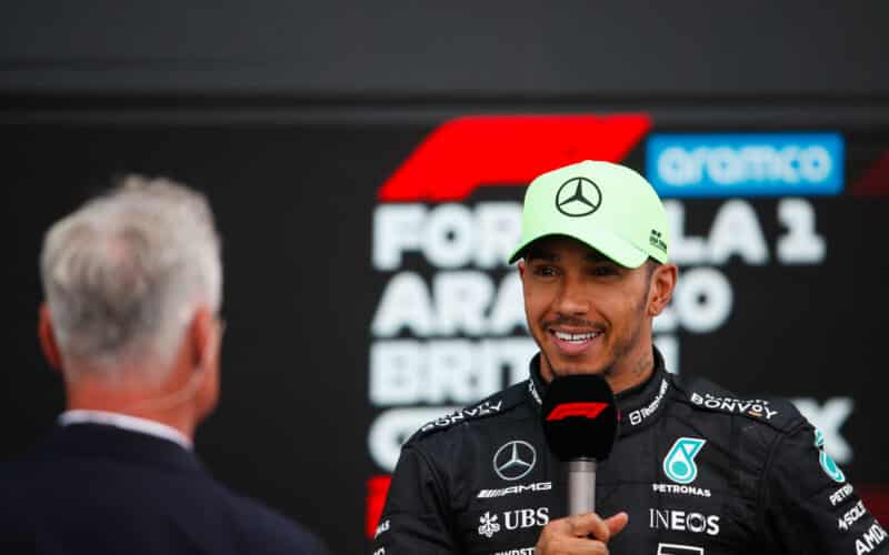 a man in a green hat talking to a man in a black suit