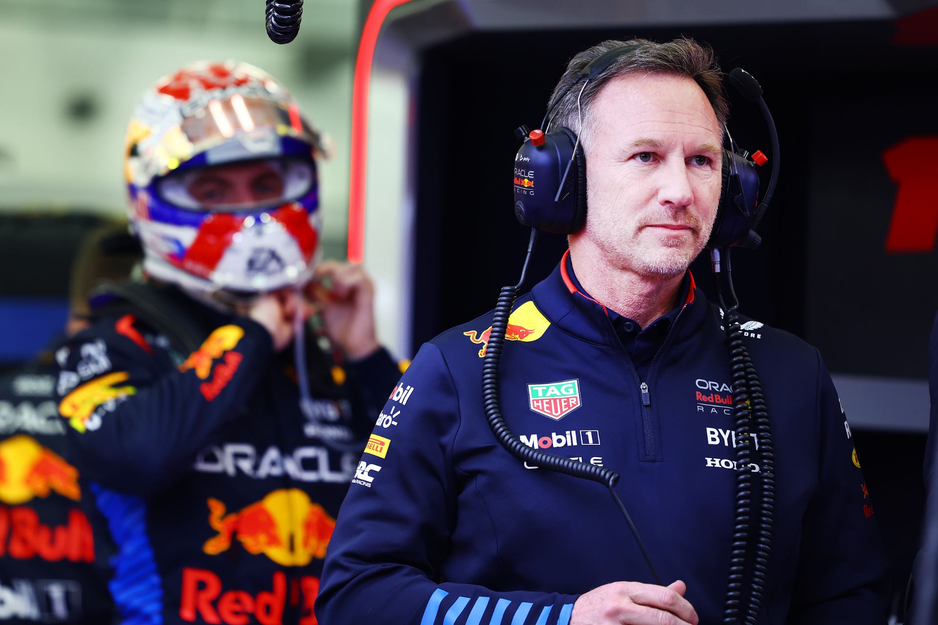 a man in a red bull racing suit with headphones on